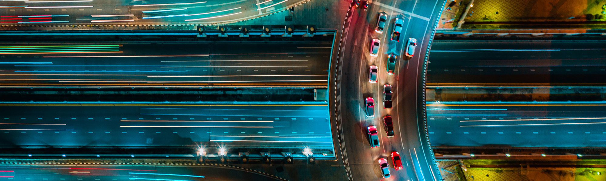 overhead view of colorful highway curve with cars at night