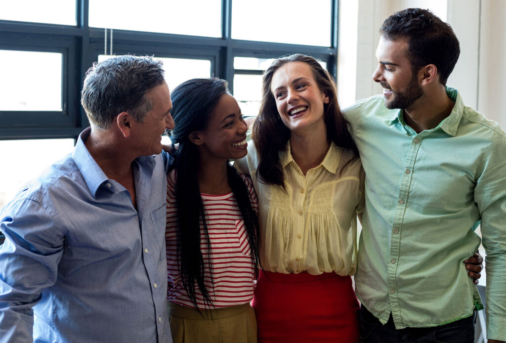 Four people work together, the banner for a state of belonging: staying curious and building connection in pride month and beyond