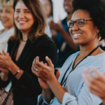 Several people attend a learning event and are standing and applauding.