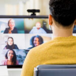 An employee attends a virtual workshop at a computer as part of a blended learning program.
